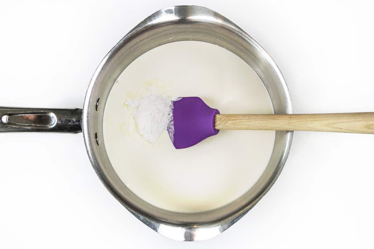 Heavy whipping cream is added to the cornstarch, granulated sugar, and a pinch of salt in the saucepan.