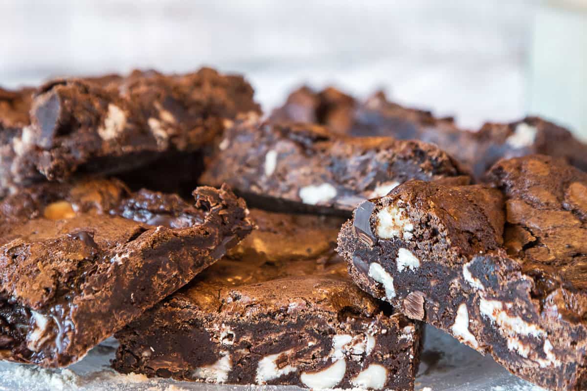 Fudgy triple chocolate brownies cut into squares on a plate.