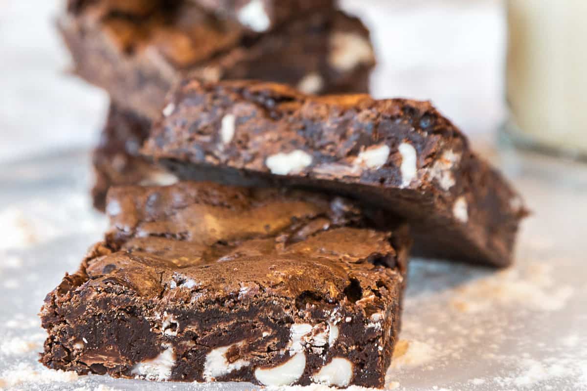 Triple chocolate brownie cut into squares on a plate.