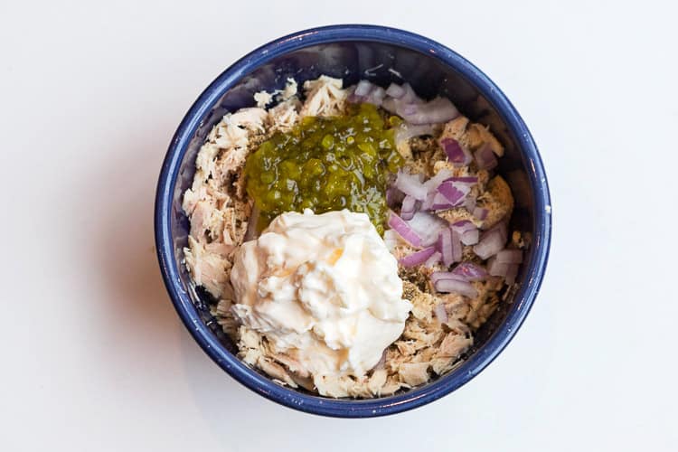 Albacore, mayonnaise, relish, and red onions in a bowl.