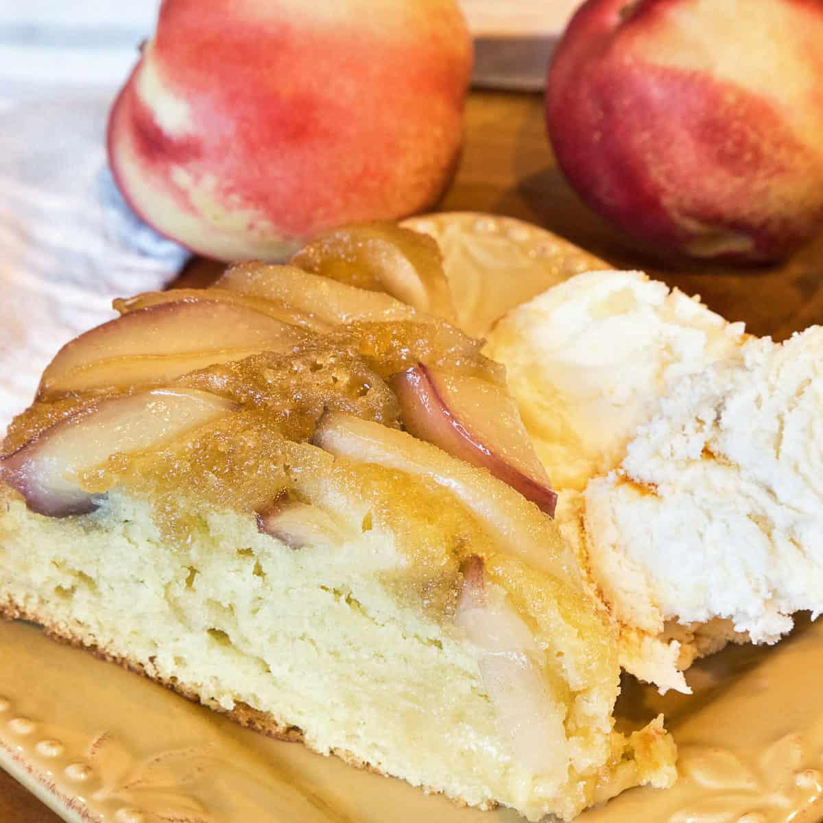 White nectarine cake upside down on a plate with ice cream.